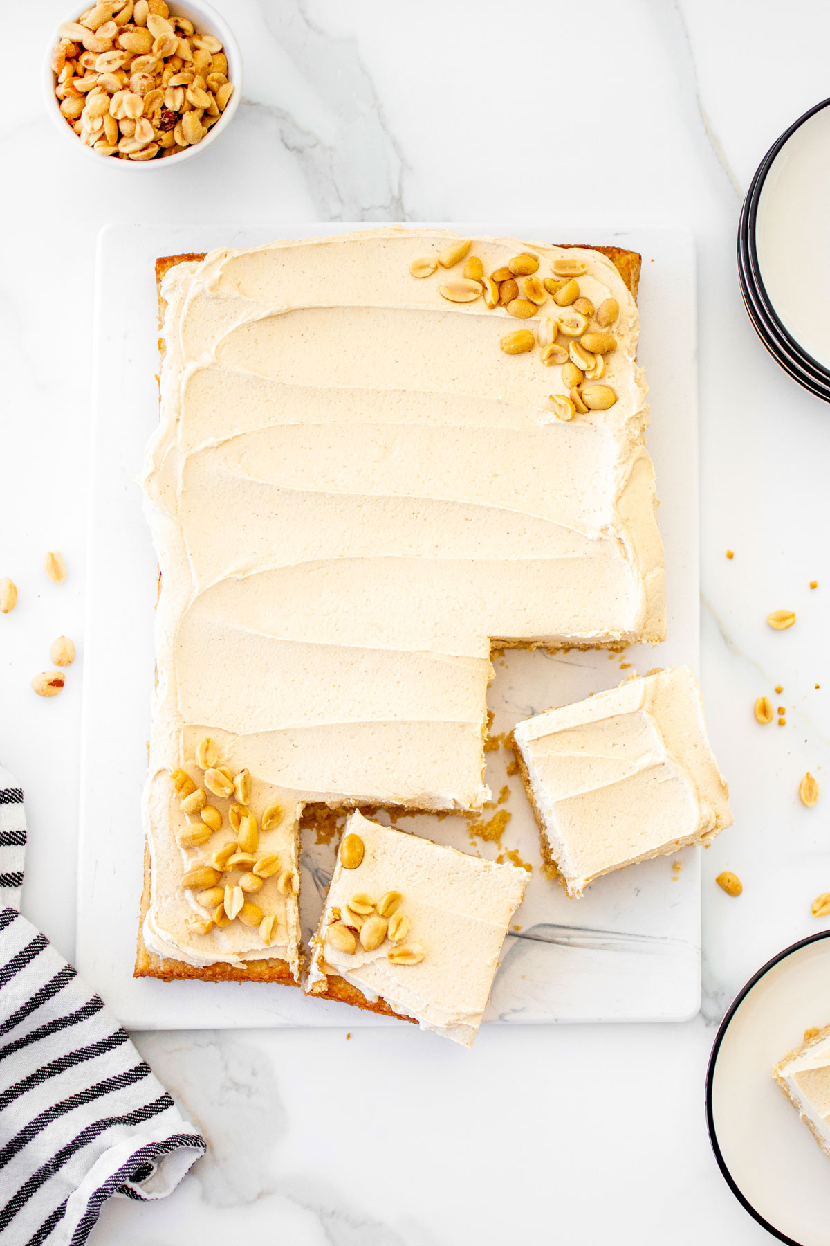 eggless peanut butter sheet cake on a white marble counter cut into a couple slices.