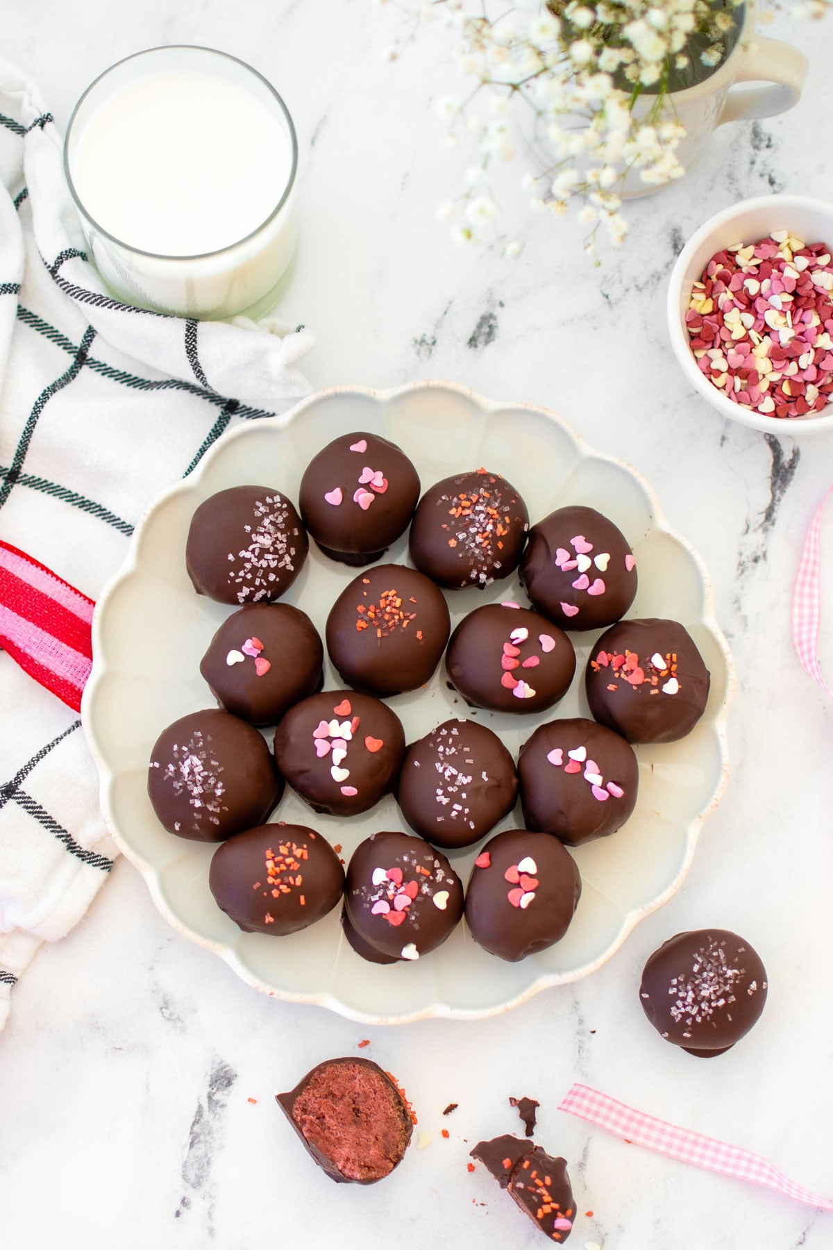 eggless red velvet sourdough cake balls with pink sprinkles on a plate on a white marble table.