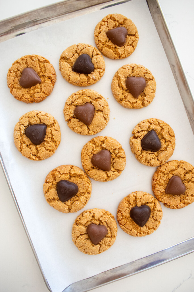 eggless valentine's peanut butter blossoms on a baking sheet on a white marble counter.