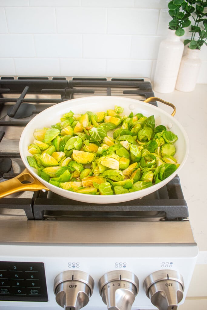 sesame ginger brussels sprouts cooking in a large skillet over the stovetop.