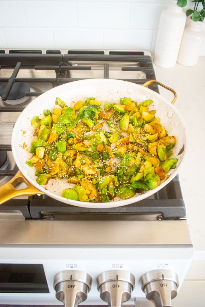 sesame ginger brussels sprouts caramelized with sesame seeds in a large skillet over the stovetop.