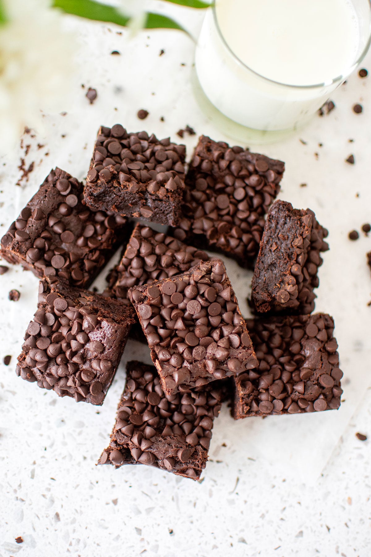 sourdough chocolate chip brownies cut into squares on a white counter with a glass of milk.