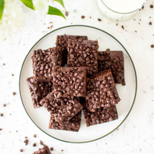 sourdough chocolate chip brownies on a plate on a white stone counter with fresh flowers.