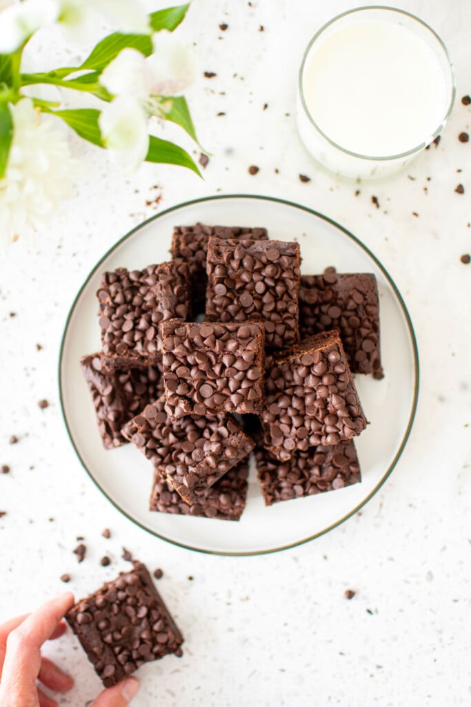 sourdough chocolate chip brownies on a plate on a white stone counter with fresh flowers.