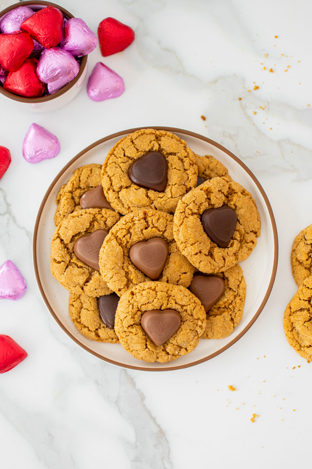 valentine's peanut butter blossoms on a plate on a marble counter with red and pink chocolate wrapped hearts.