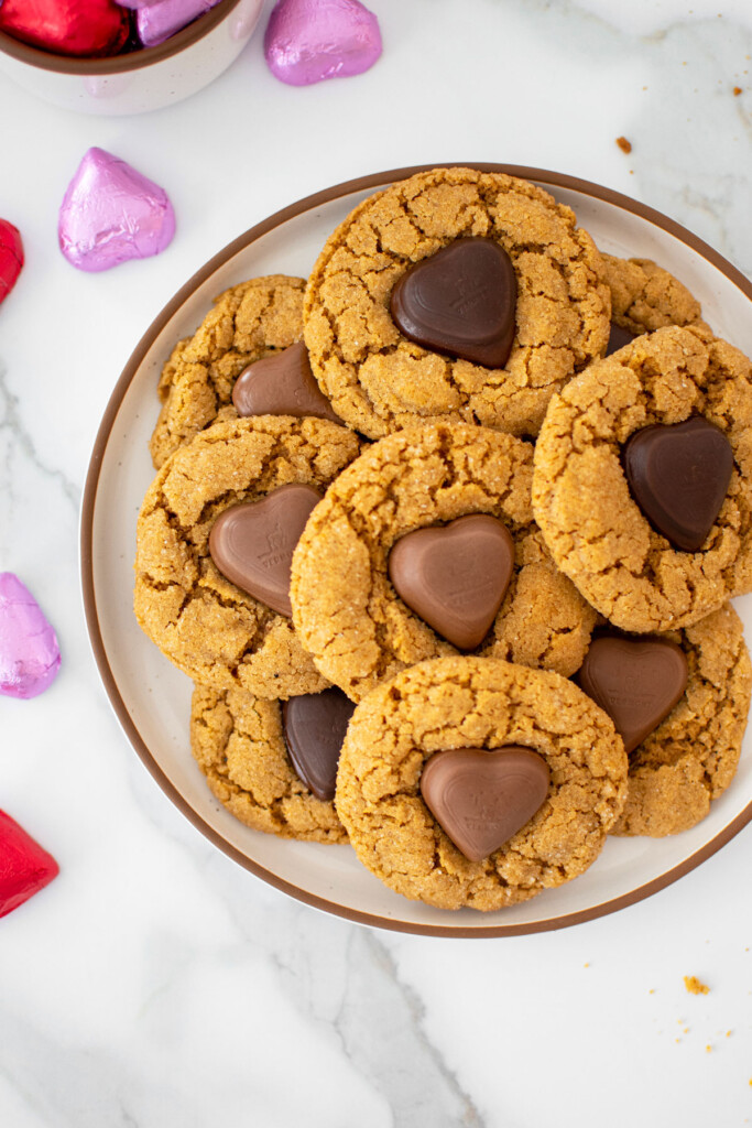 valentine's peanut butter blossoms on a plate on a marble counter with red and pink chocolate wrapped hearts.
