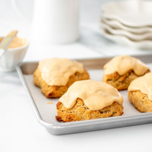 banana scones with peanut butter glaze on a baking sheet on a marble counter.