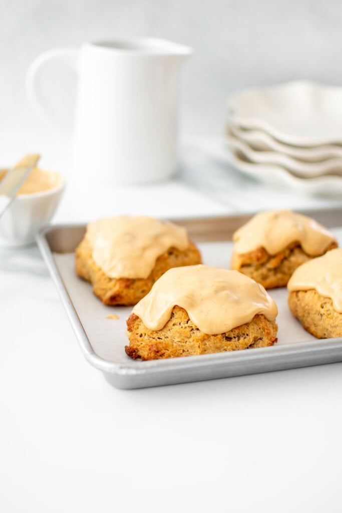 banana scones with peanut butter glaze on a baking sheet on a marble counter.