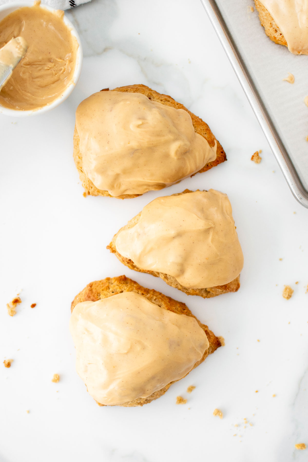 banana scones with peanut butter glaze on a white marble counter.