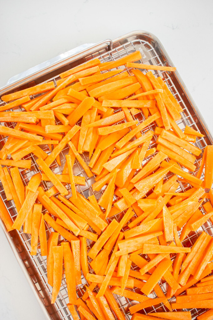 garlic lemons weet potato fries on a baking sheet on a kitchen countertop.