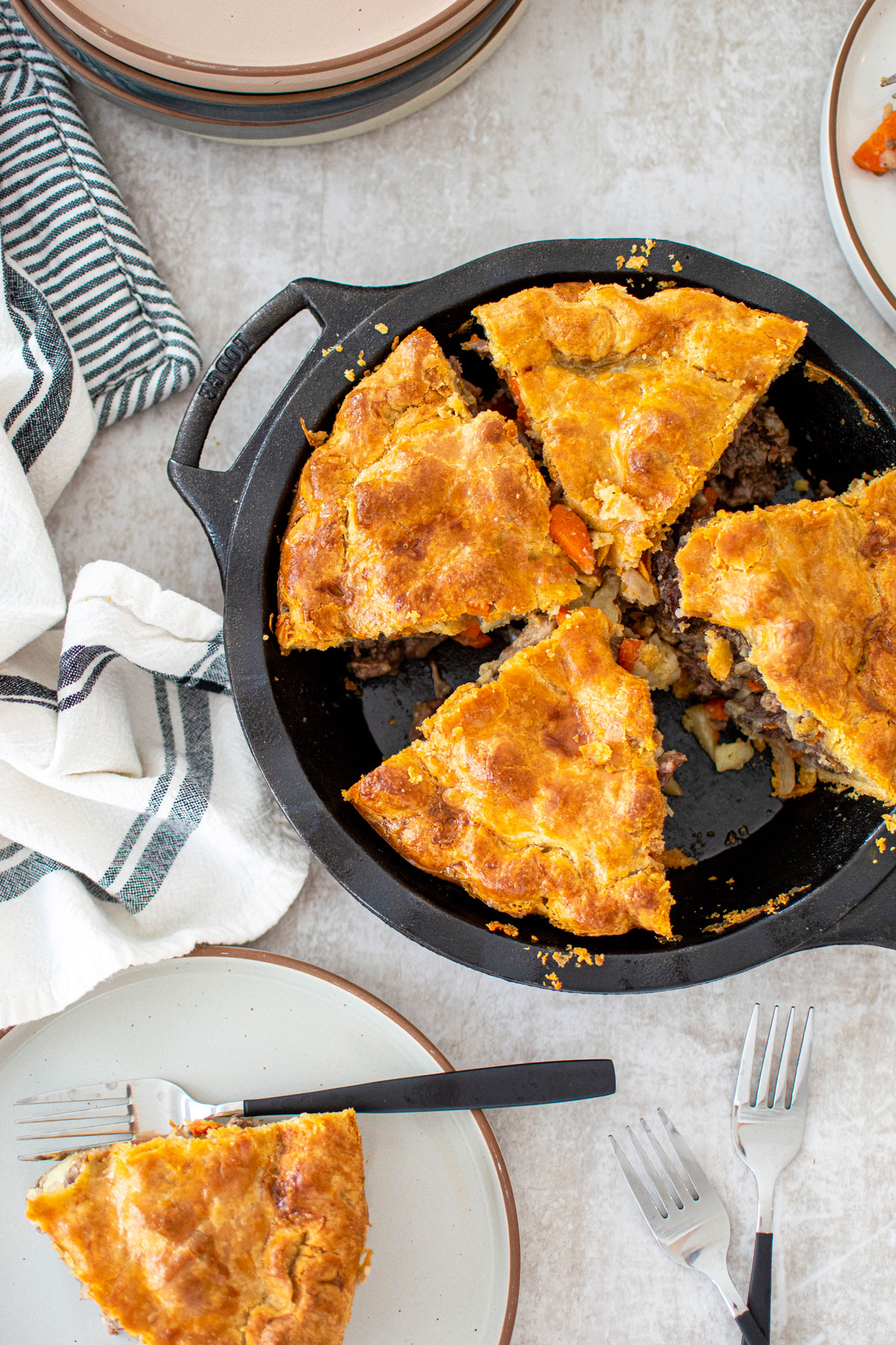 hearty meat pie in a cast iron pie pan cut into slices on the dinnner table.