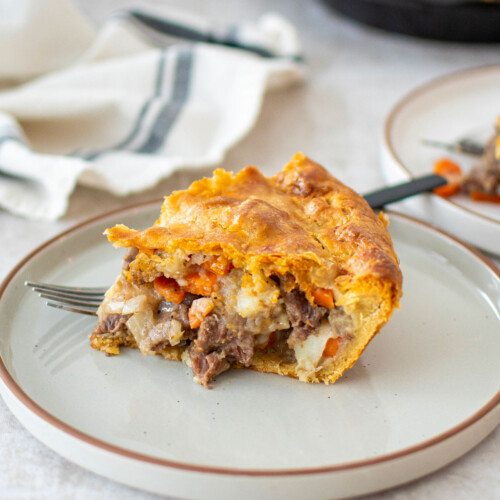 slice of a hearty meat pie with chuck roast on a plate on the dinner table.