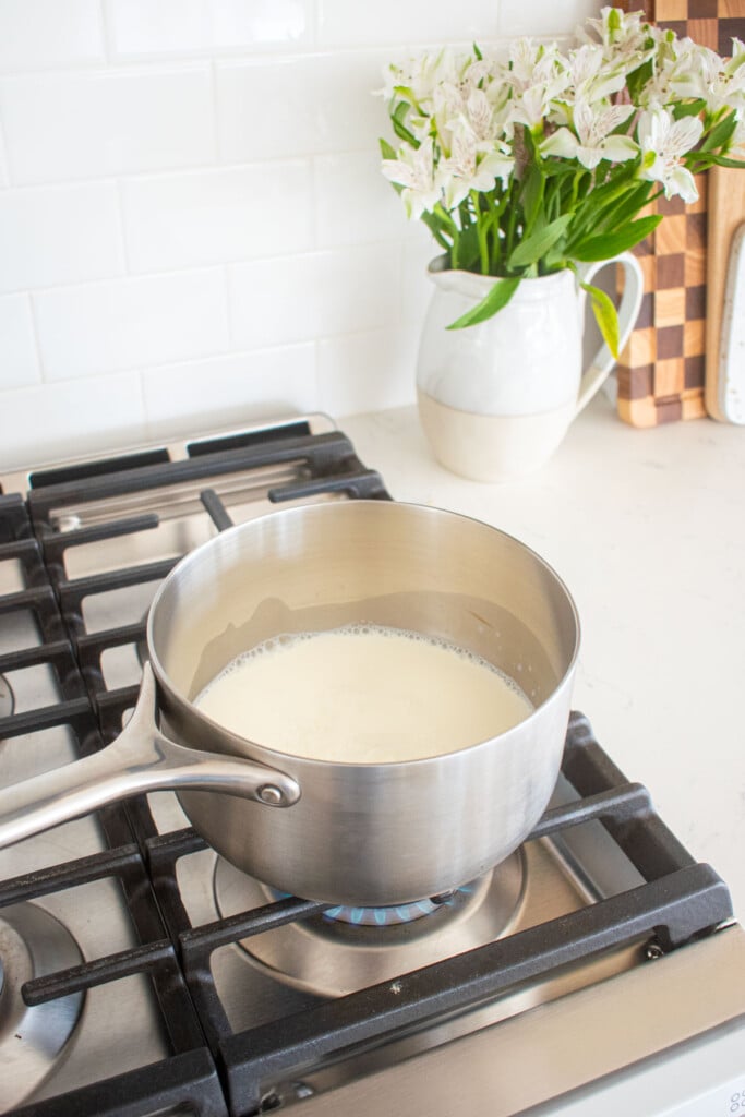 stainless steel pot of milk and sugar on a stovetop.