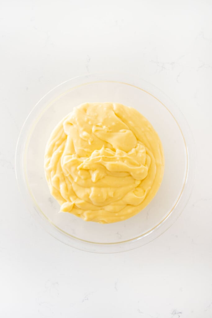 homemade vanilla malt pudding in a glass mixing bowl on a white marble counter.