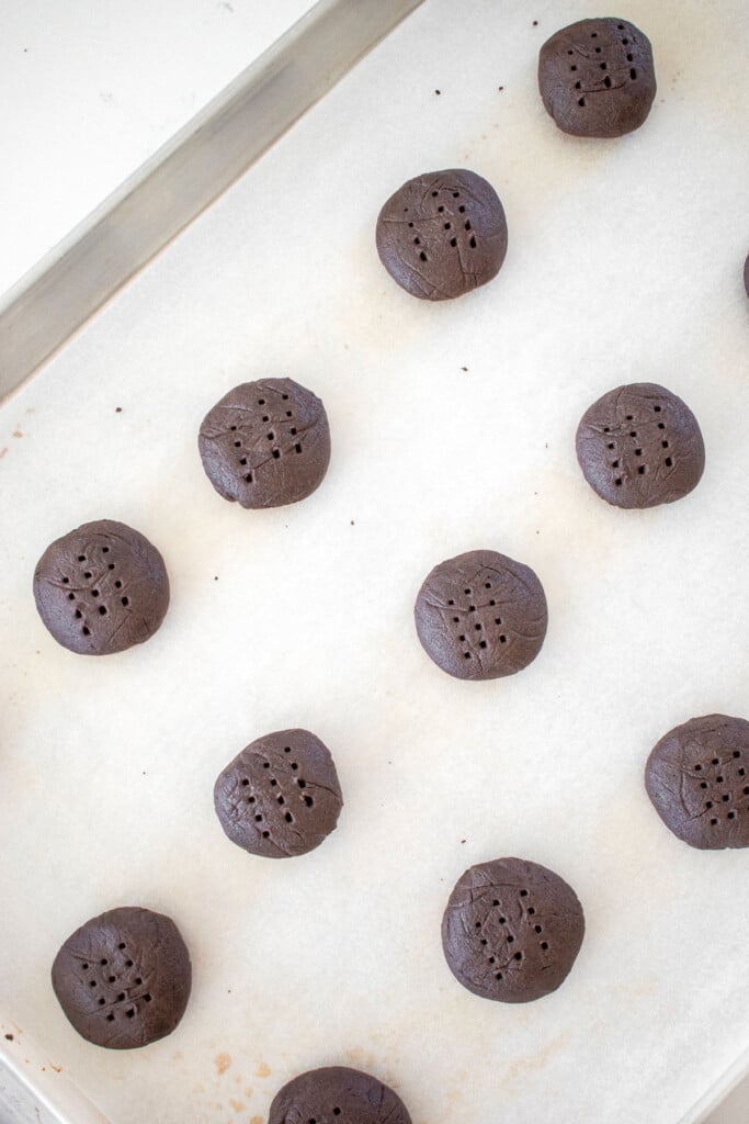 oreo cookie dough balls on a baking sheet on a marble counter.