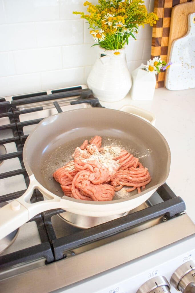 raw ground turkey with spices in a skillet on the stovetop.