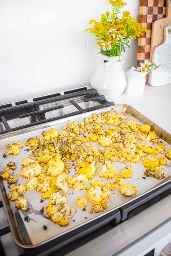 baking sheet with roasted cauliflower cooling on top of an ovne.