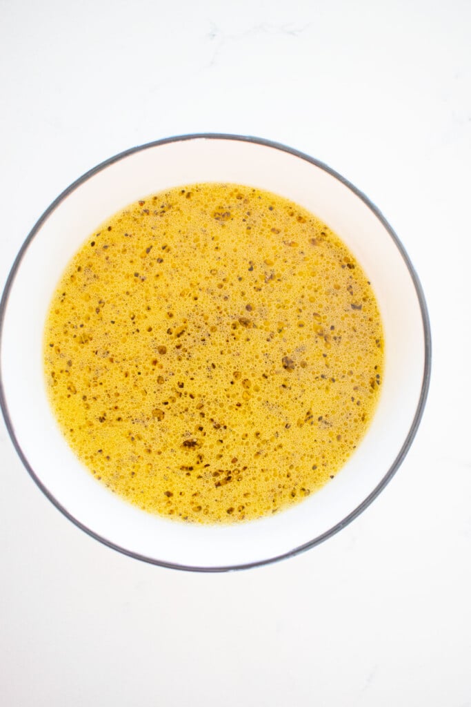 homemade lemon dressing in a bowl on a marble counter.