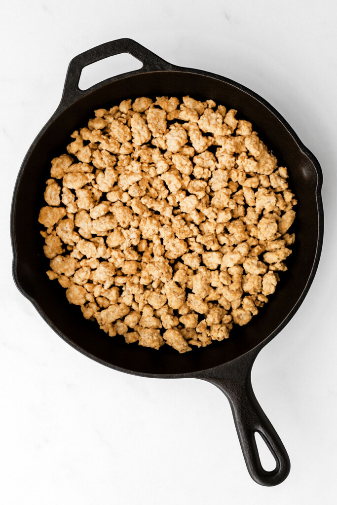 cooked ground turkey in a cast iron skillet on a white marble countertop.