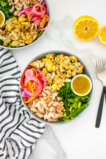 roasted cauliflower turkey salad with lemon dressing in a bowl on a white marble countertop.