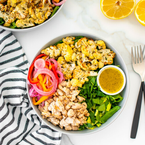 roasted cauliflower turkey salad with lemon dressing in a bowl on a white marble countertop.