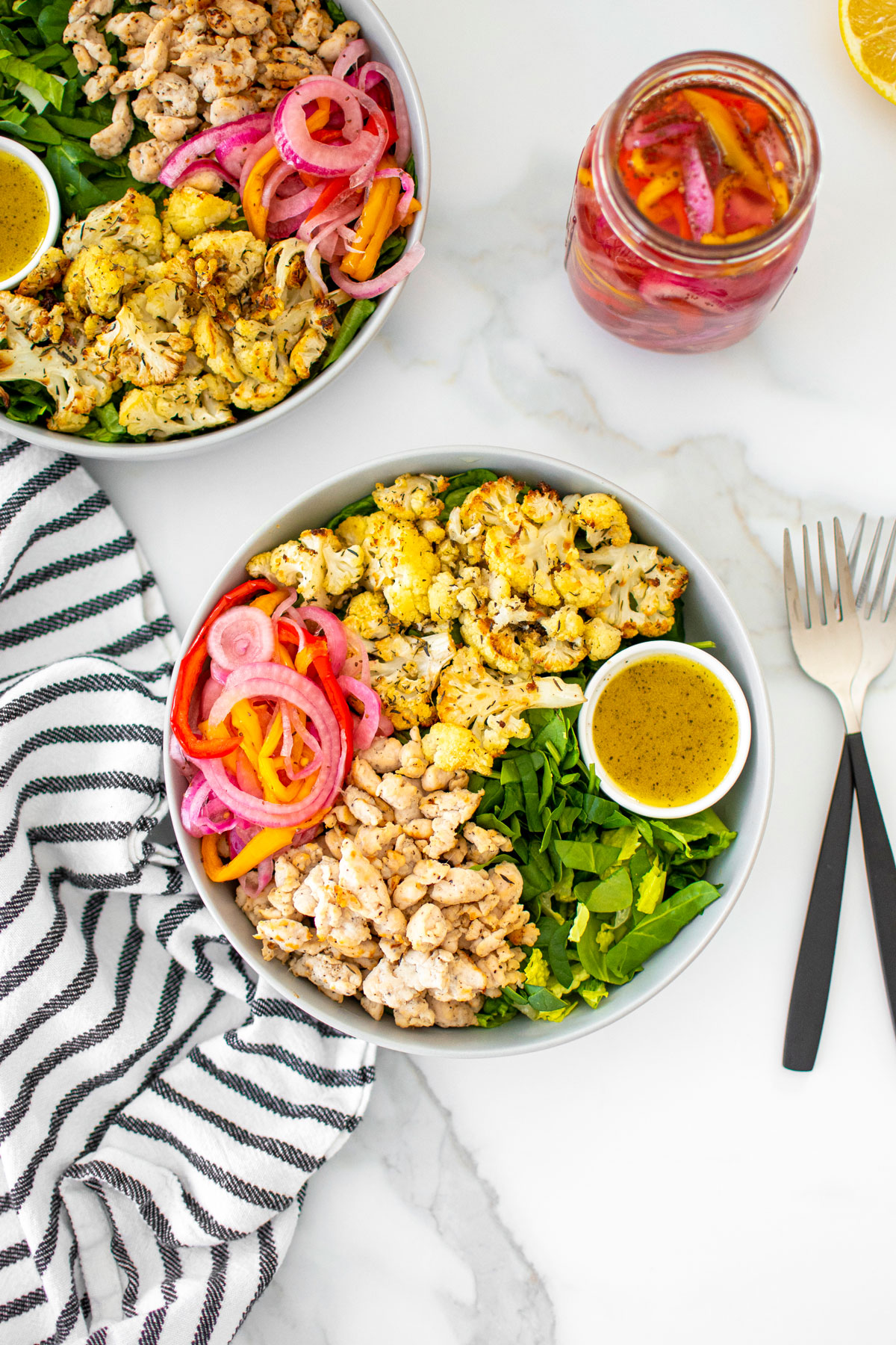 roasted cauliflower turkey salad with lemon dressing in a bowl on a white marble countertop.