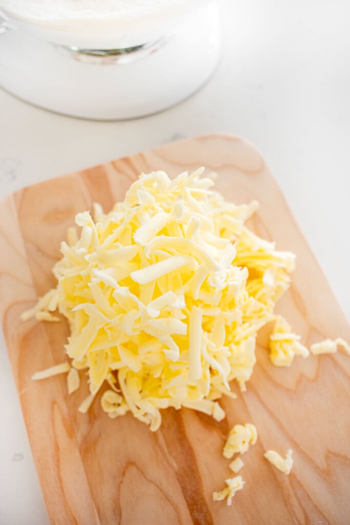 grated butter on a wood cutting board on a marble counter.