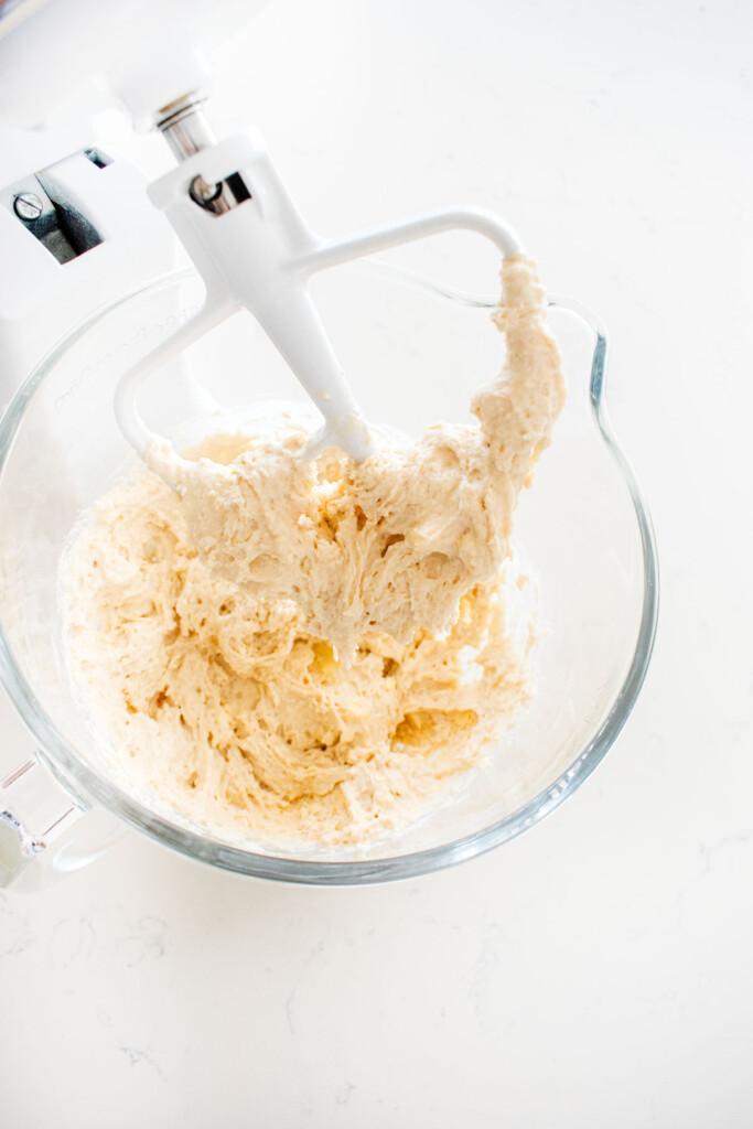 sourdough irish soda bread dough that looks sticky mixed in a mixer on a white marble counter.