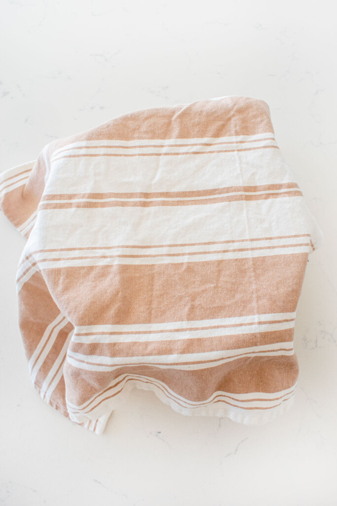 mixing bowl covered with a kitchen towel on a white marble counter.