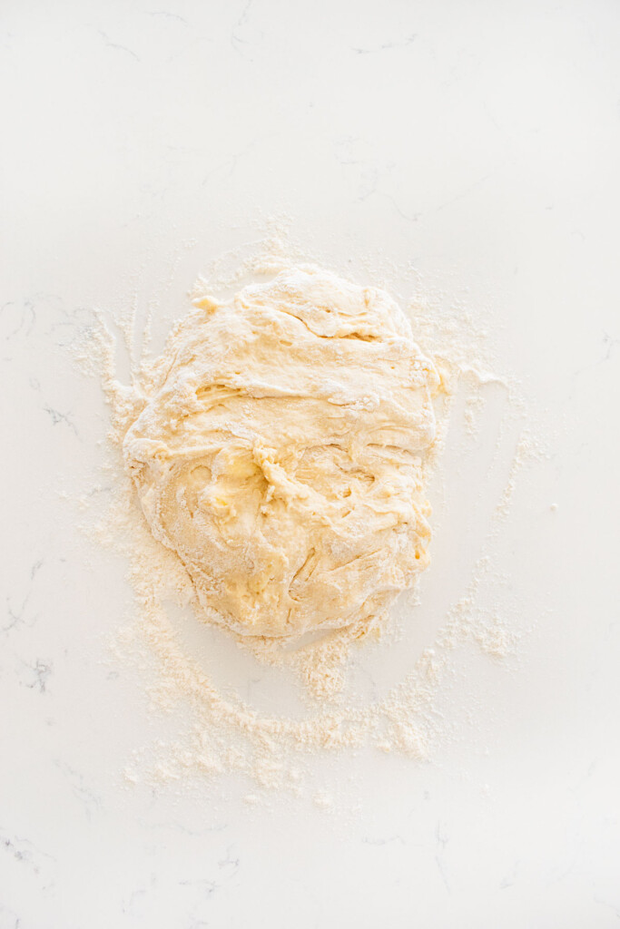sourdough irish soda bread dough on a floured white marble counter.