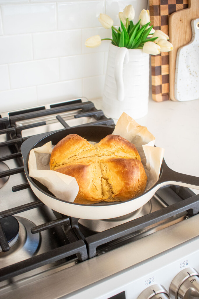 baked sourdough irish soda bread in a cast iron skillet cooling on top of an oven.