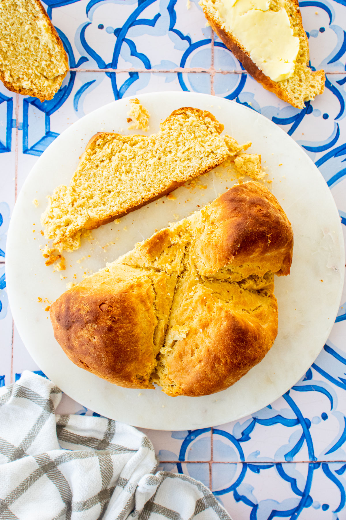 sourdough irish soda bread sliced on a marble serving board on a blue tile table.