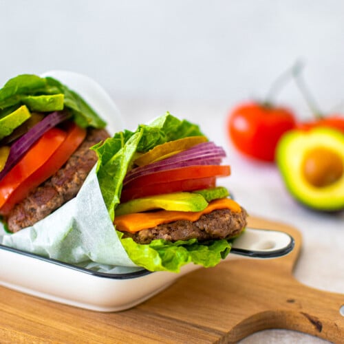 avocado lettuce wrap burgers in a serving dish on a wood board.