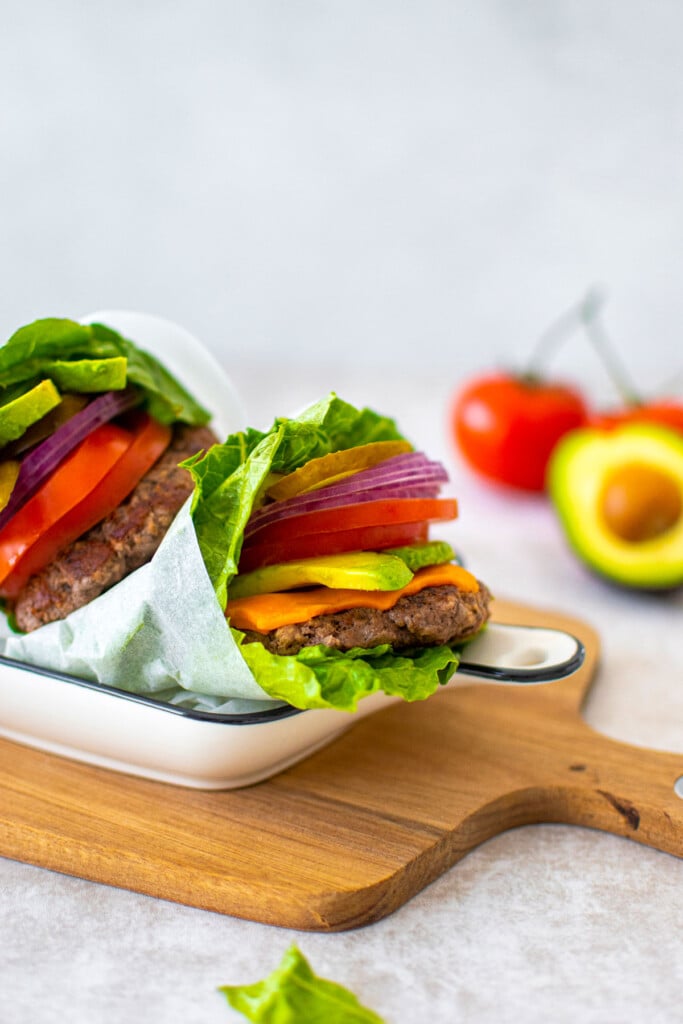 avocado lettuce wrap burgers in a serving dish on a wood board.