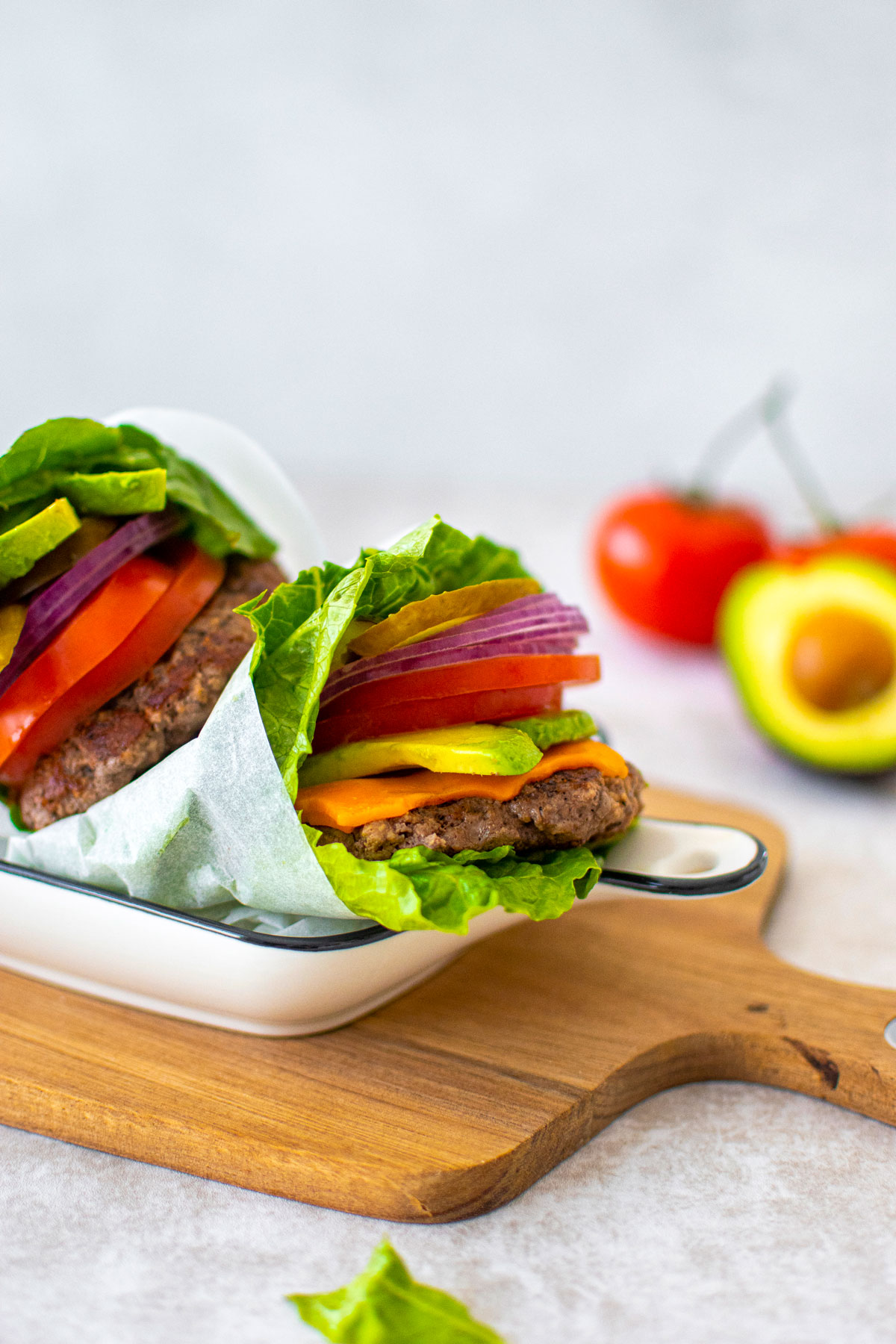 avocado lettuce wrap burgers in a serving dish on a wood board.