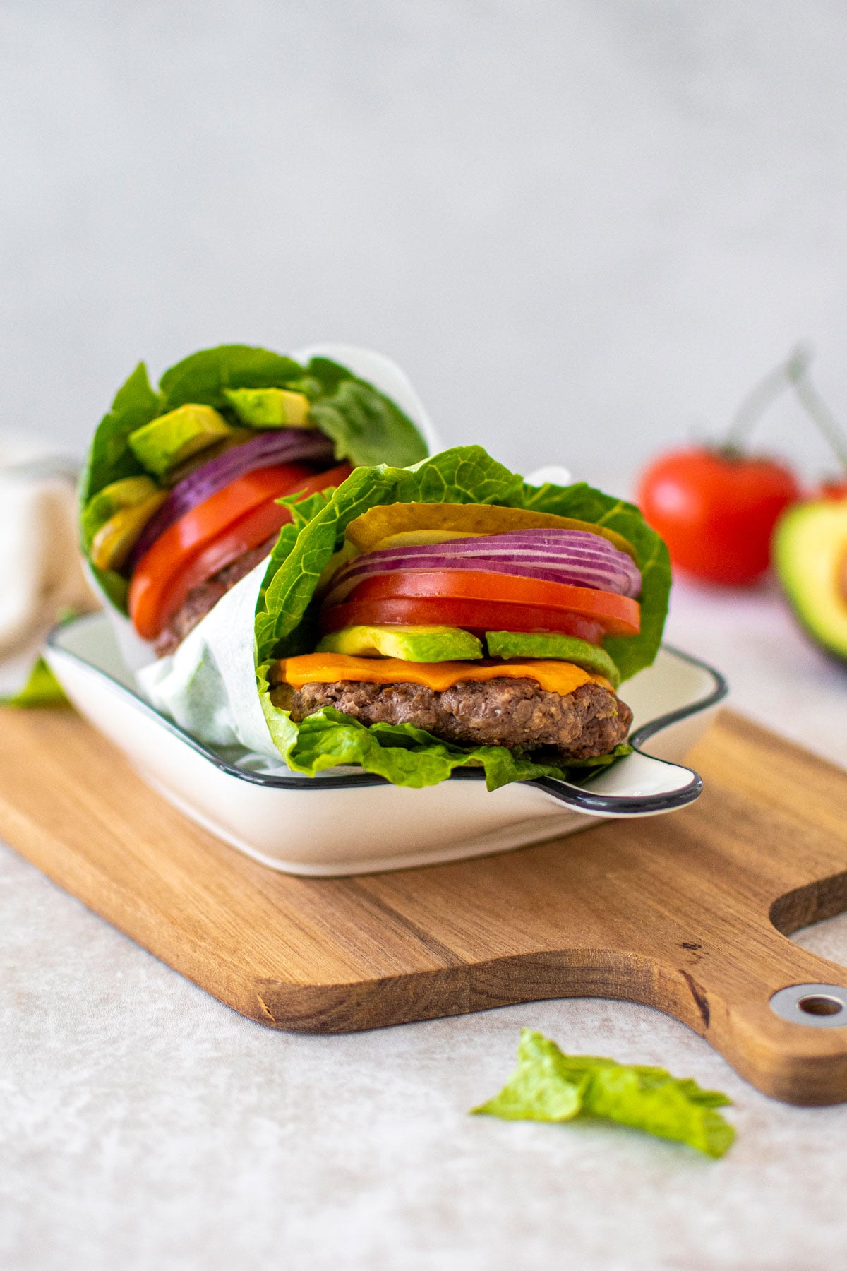 avocado lettuce wrap burgers in a serving dish on a wood board.