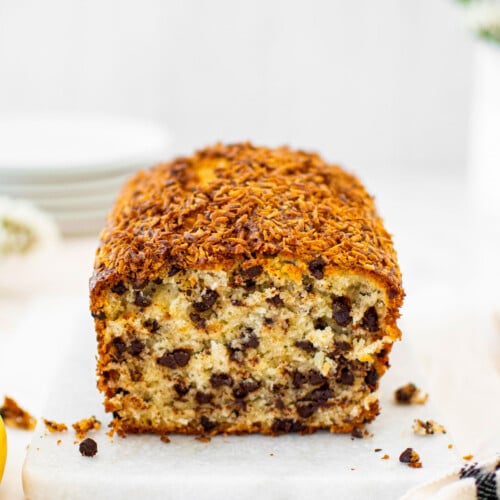 coconut chocolate chip banana bread loaf on a white marble board.