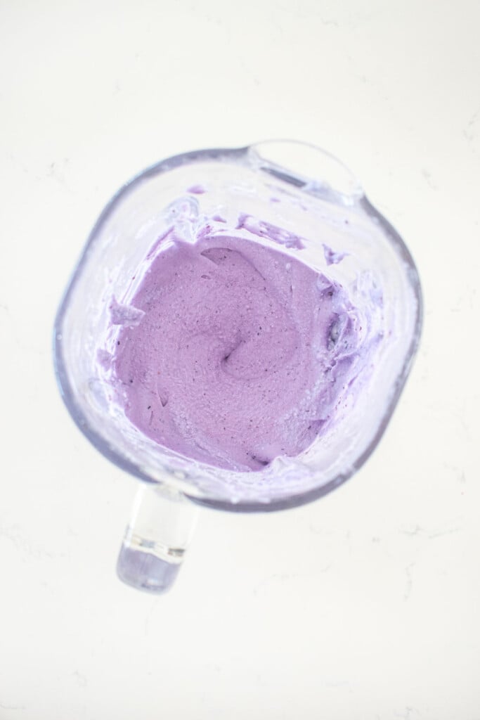 homemade blueberry pup cup blended to a smooth creamy mixture in a glass blender on a white marble counter.