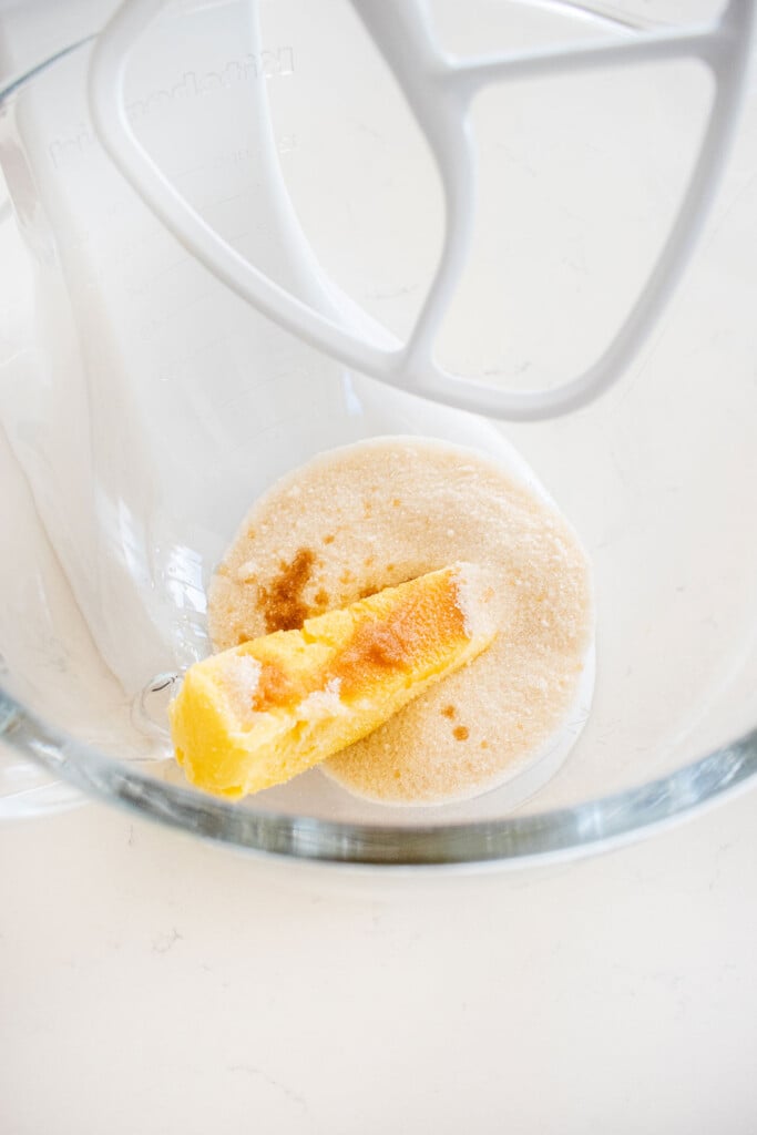 butter, sugar and vanilla in a glass mixing bowl on a marble counter.