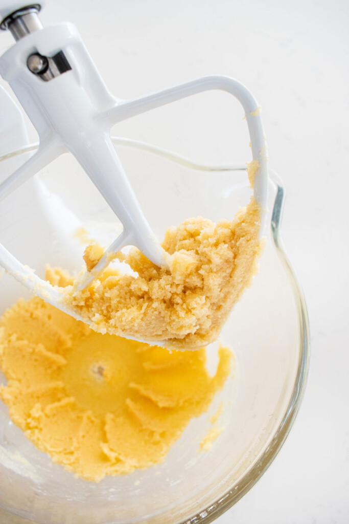 creamed butter and sugar in a glass mixing bowl on a marble counter.