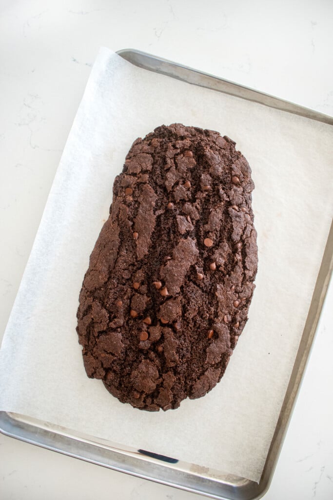 chocolate espresso biscotti log on a baking sheet on a marble counter.