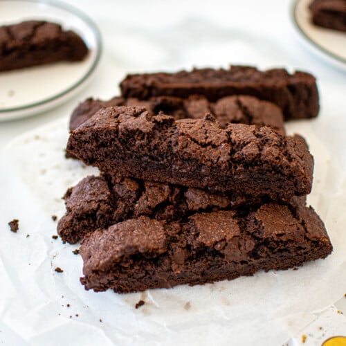chocolate espresso biscotti stacked on a marble board on a marble table.