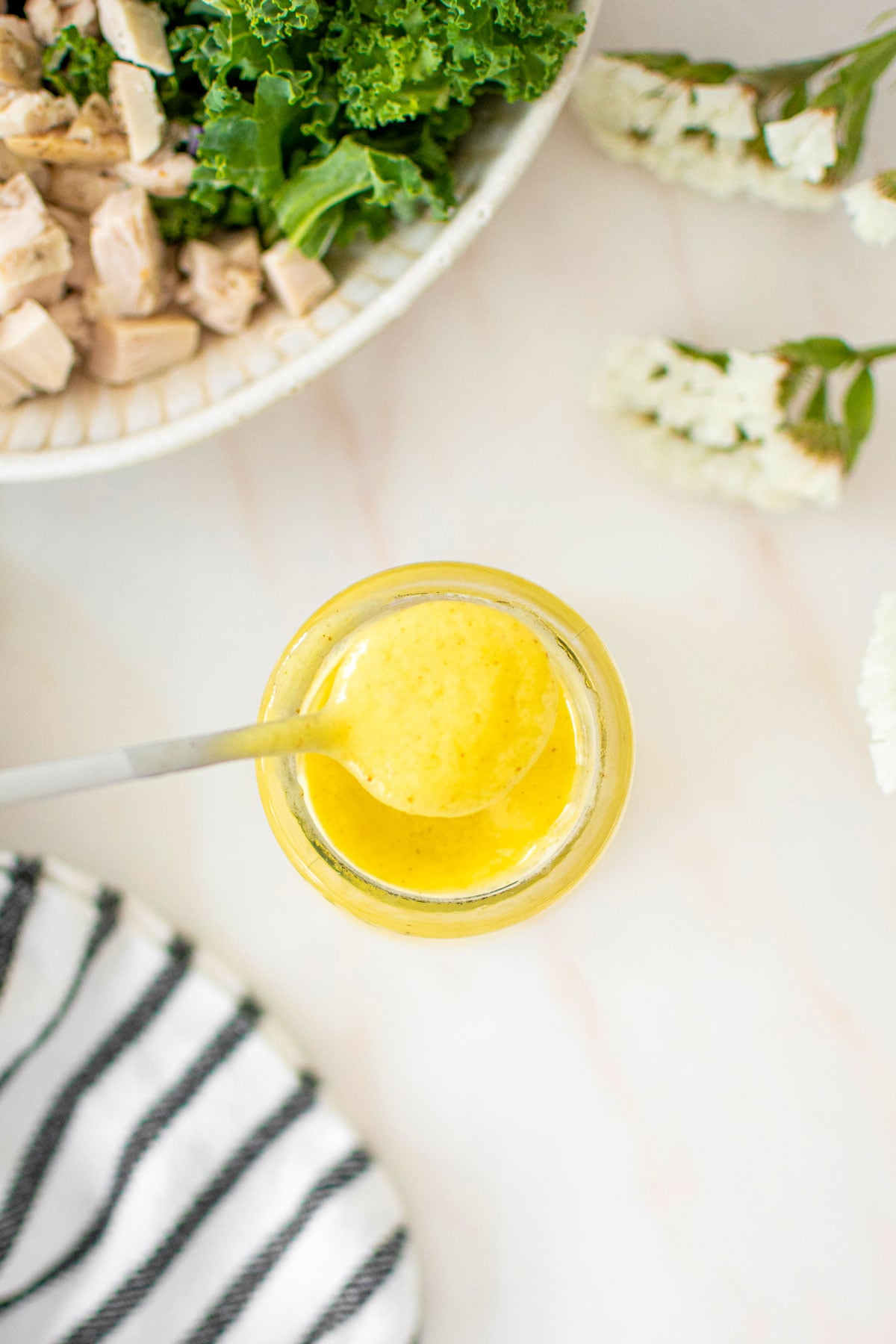 vegan honey mustard dressing in a small glass jar on a marble counter.