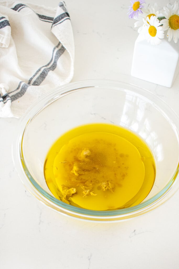glass bowl with ingredients for vegan honey mustard dressing in it on a marble counter.