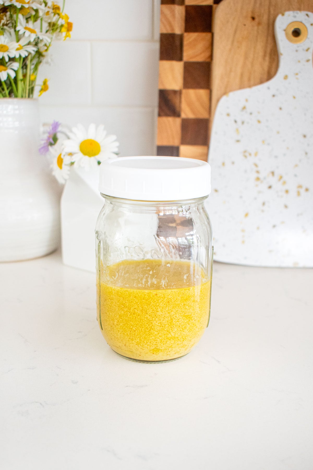 mason jar with vegan honey mustard dressing on a marble counter.
