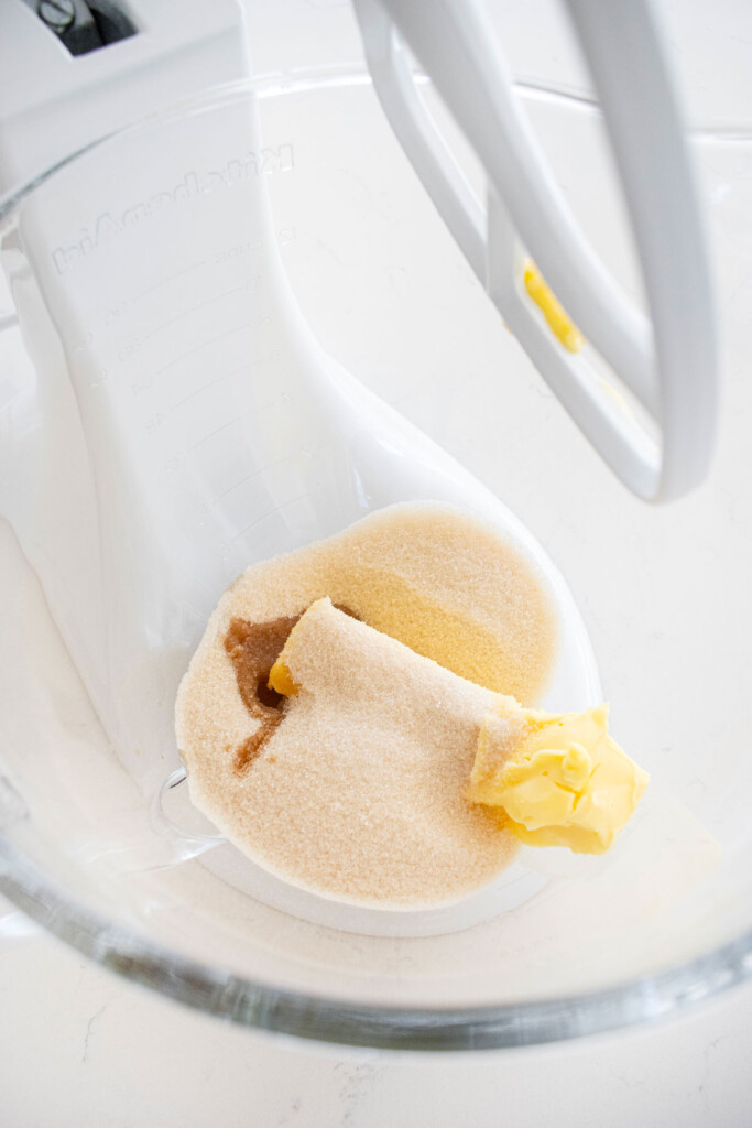butter sugar and vanilla in a glass mixing bowl on a marble counter.