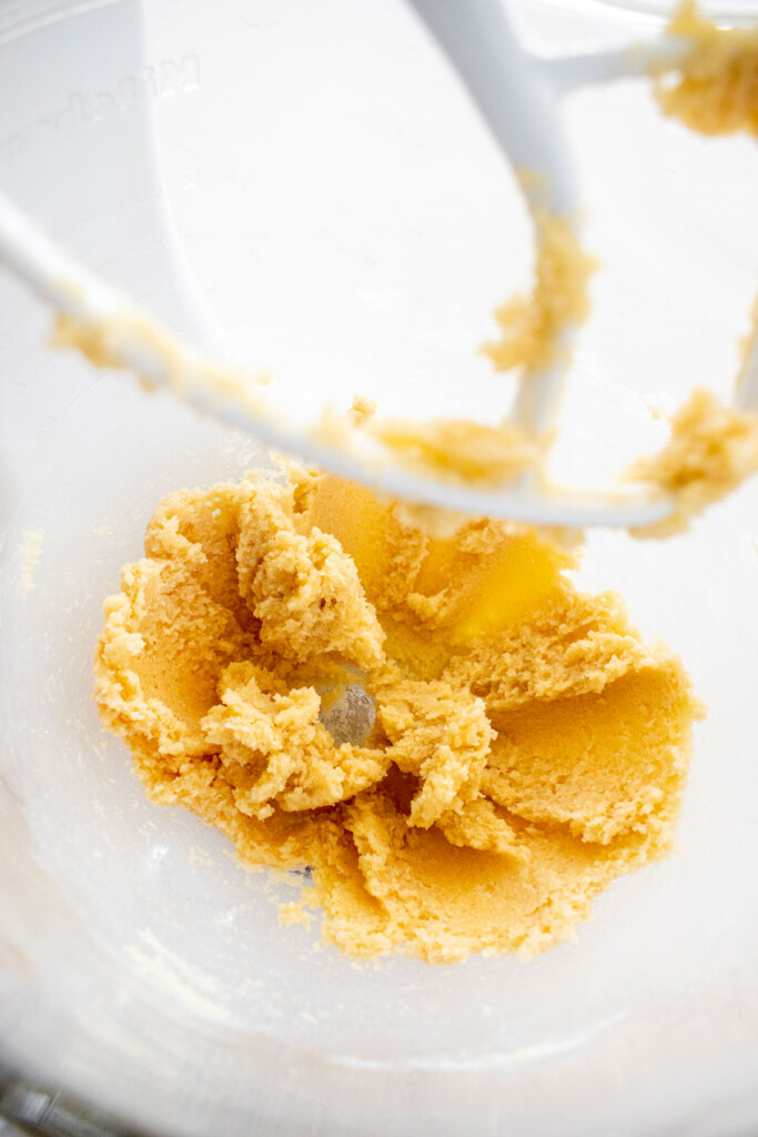 creamed butter and sugar in a glass mixing bowl on a marble counter.