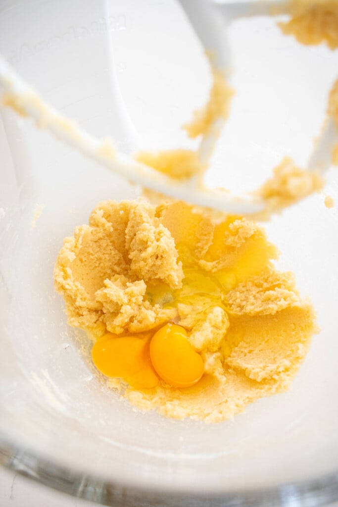 creamed butter and sugar with eggs in a glass mixing bowl on a marble counter.