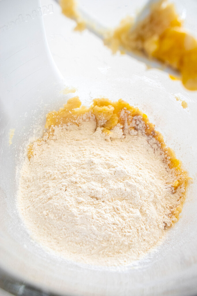 ingredients for blueberry muffin biscotti cookie dough in a glass mixing bowl on a marble counter.