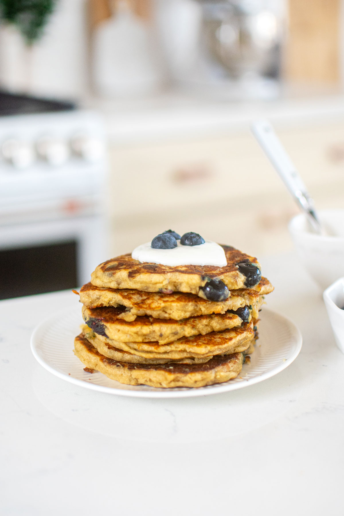 stack of blueberry pancakes for dogs with greek yogurt on top on a plate on the counter.